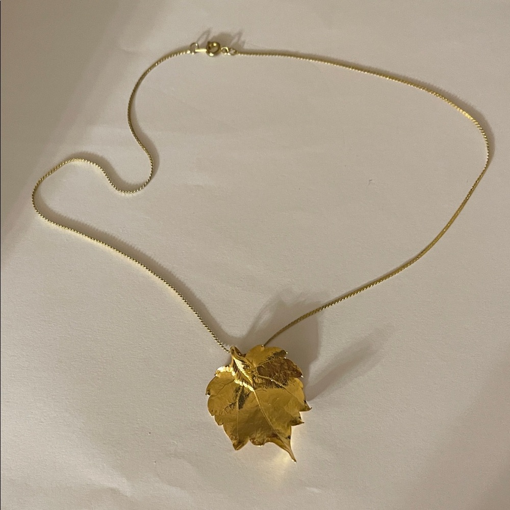 Gold tone metal necklace with leaf pendant